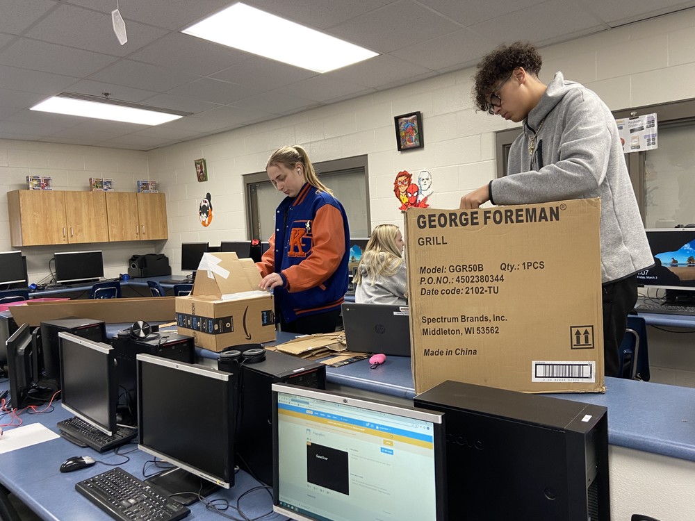 Two students unpacking cardboard boxes during business class