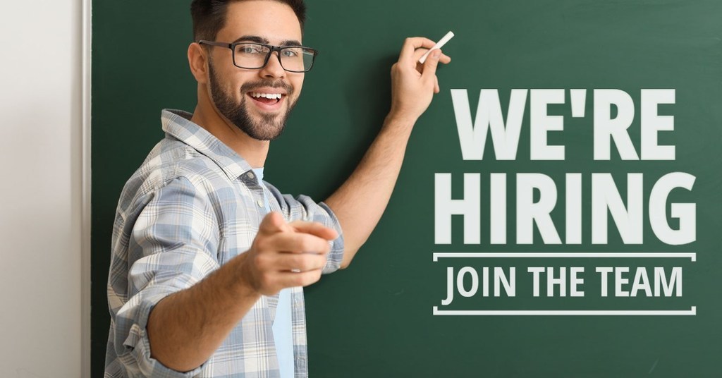 man pointing to chalkboard with text "We're Hiring - Join the Team"