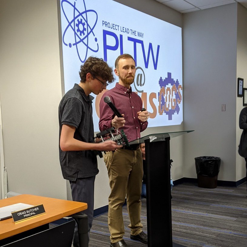 student and teacher speak at podium