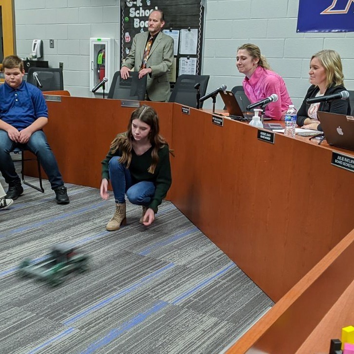 girl drive robot in front of school board members